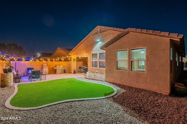 back house at twilight featuring a patio area