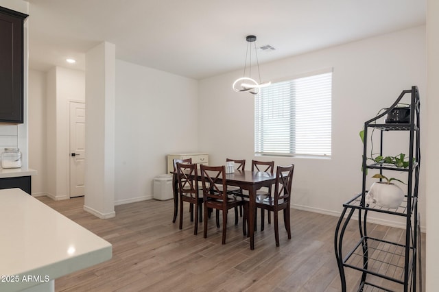 dining space with a notable chandelier and light wood-type flooring