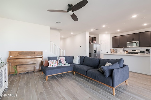 living room with sink, ceiling fan, and light wood-type flooring