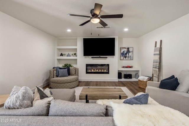 8022 E Columbus Ave, Scottsdale, AZ 85251 - living room featuring wood finished floors, a ceiling fan, a glass covered fireplace, recessed lighting, and built in shelves