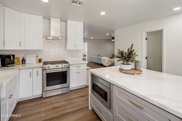 8022 E Columbus Ave, Scottsdale, AZ 85251 - kitchen with stainless steel appliances, wall chimney range hood, light wood-type flooring, recessed lighting, and decorative backsplash