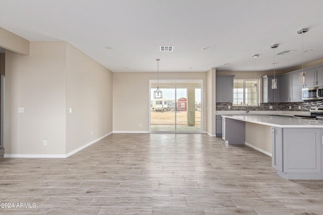 kitchen featuring gray cabinets, pendant lighting, appliances with stainless steel finishes, and decorative backsplash