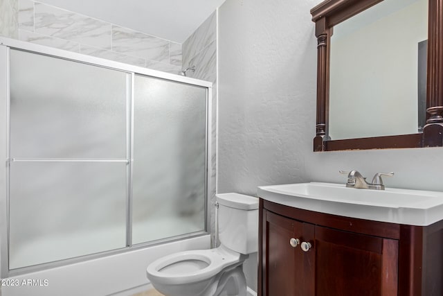 full bathroom featuring combined bath / shower with glass door, vanity, and toilet