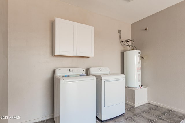 laundry room with dark tile patterned flooring, cabinets, independent washer and dryer, and water heater