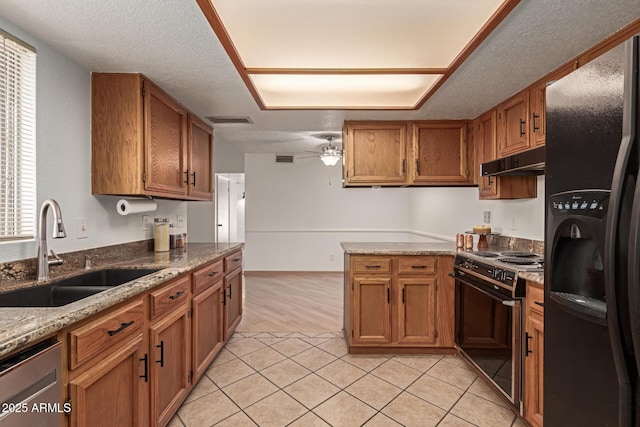 kitchen featuring visible vents, black refrigerator with ice dispenser, electric range oven, a sink, and under cabinet range hood