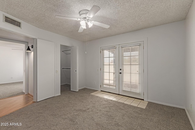 interior space with a ceiling fan, french doors, visible vents, and a textured ceiling