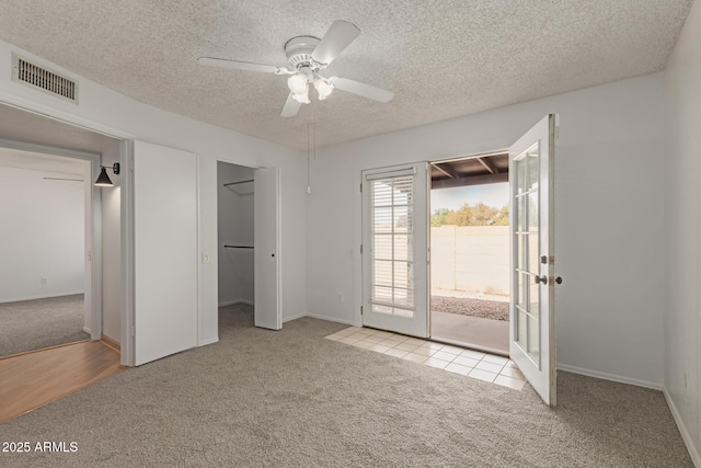 unfurnished bedroom featuring a textured ceiling, carpet floors, visible vents, access to exterior, and french doors