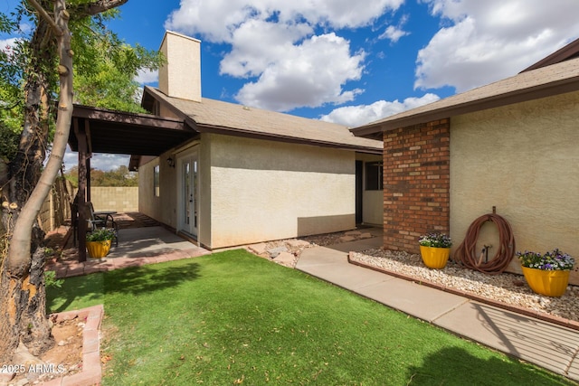 back of house with a lawn, a chimney, fence, a patio area, and stucco siding