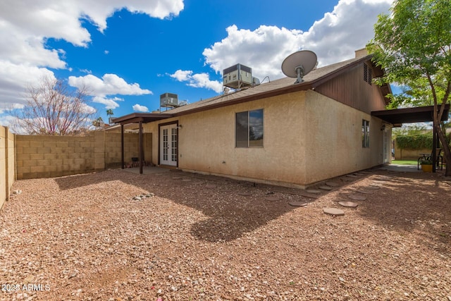 back of property with fence private yard, stucco siding, central AC, and french doors