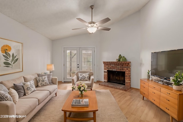 living room featuring a ceiling fan, lofted ceiling, light wood-style flooring, french doors, and a fireplace