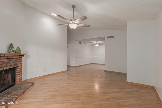 unfurnished living room with a ceiling fan, lofted ceiling, a brick fireplace, and light wood finished floors