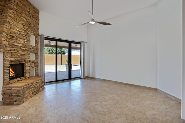 unfurnished living room with ceiling fan, light tile patterned floors, and a stone fireplace