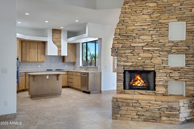 kitchen with a center island, tasteful backsplash, wall chimney range hood, sink, and stainless steel appliances