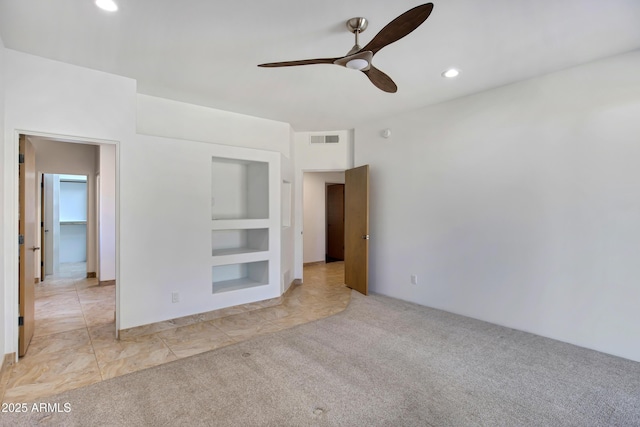 carpeted empty room with built in shelves and ceiling fan