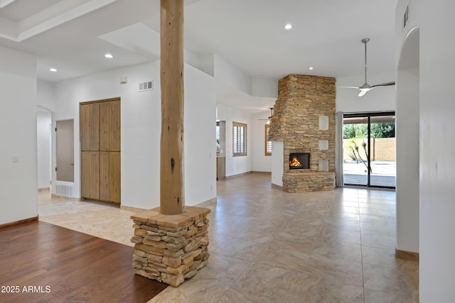 unfurnished living room with a fireplace, a towering ceiling, and ceiling fan