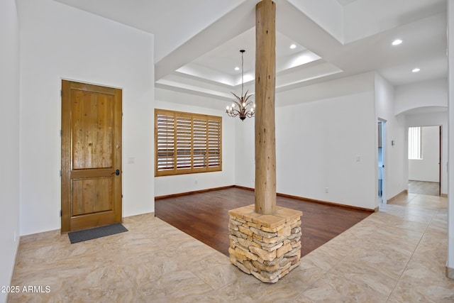 spare room with a wealth of natural light, a raised ceiling, and a chandelier