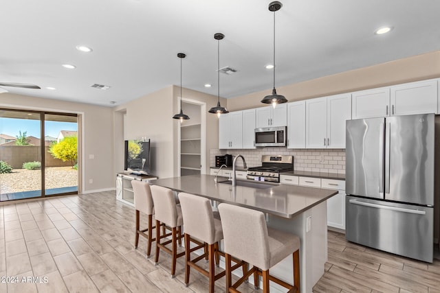 kitchen with white cabinetry, sink, an island with sink, pendant lighting, and appliances with stainless steel finishes