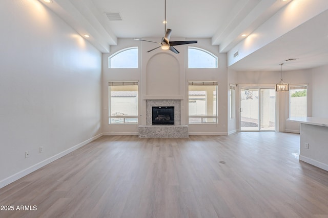 unfurnished living room featuring ceiling fan, light hardwood / wood-style flooring, and a high ceiling