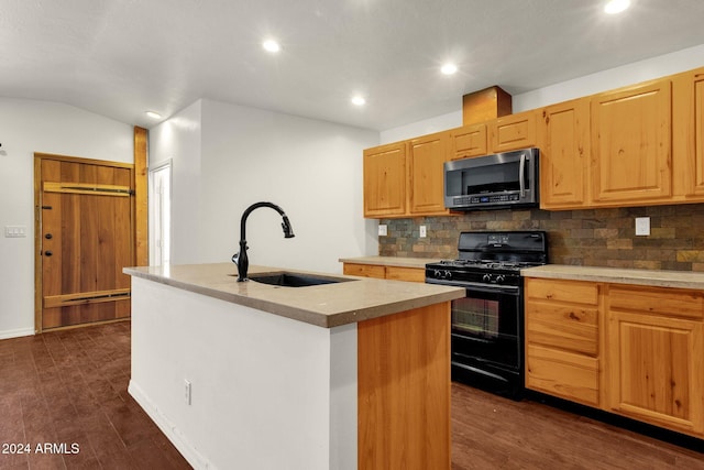 kitchen with sink, dark hardwood / wood-style floors, black gas stove, decorative backsplash, and a center island with sink