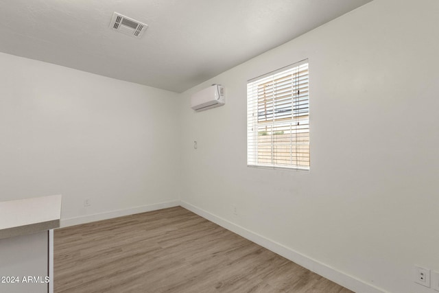 spare room featuring a wall unit AC and light hardwood / wood-style flooring