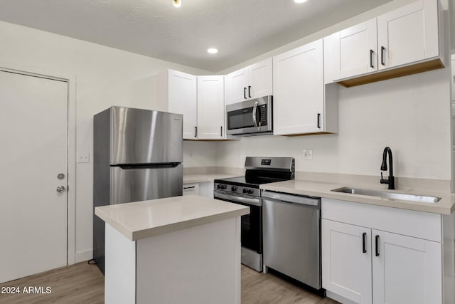 kitchen featuring white cabinetry, sink, light hardwood / wood-style flooring, a kitchen island, and appliances with stainless steel finishes