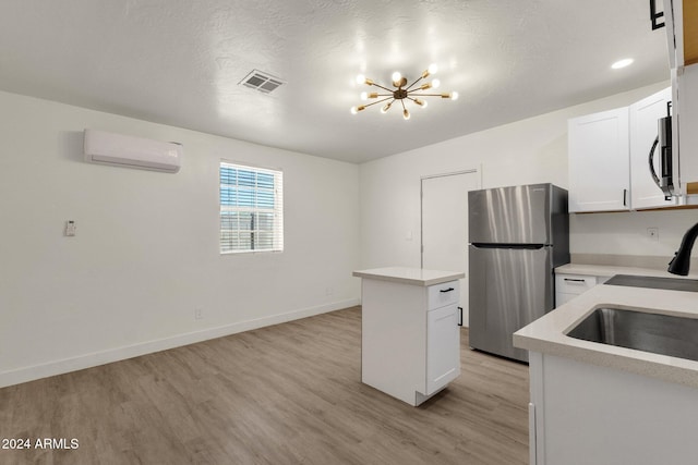 kitchen with stainless steel appliances, a wall mounted air conditioner, a kitchen island, light hardwood / wood-style floors, and white cabinets