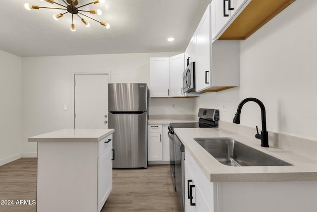 kitchen featuring white cabinets, a notable chandelier, light wood-type flooring, and appliances with stainless steel finishes