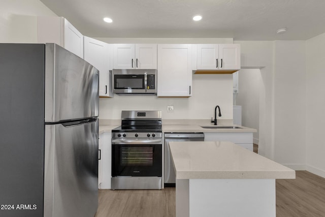 kitchen with stainless steel appliances, white cabinetry, light hardwood / wood-style floors, and sink