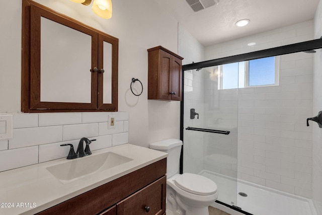 bathroom featuring vanity, toilet, walk in shower, and tasteful backsplash