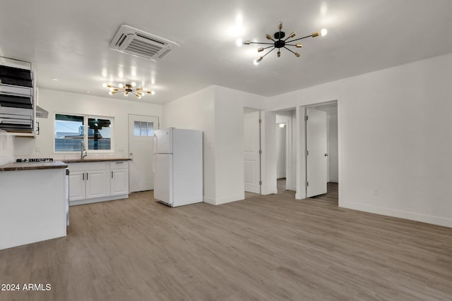 kitchen featuring sink, white fridge, light hardwood / wood-style floors, white cabinets, and ceiling fan with notable chandelier