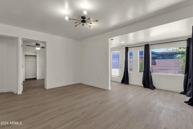 spare room featuring a chandelier and light hardwood / wood-style flooring