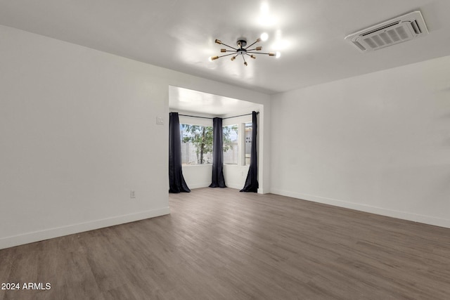 unfurnished room with hardwood / wood-style flooring and an inviting chandelier