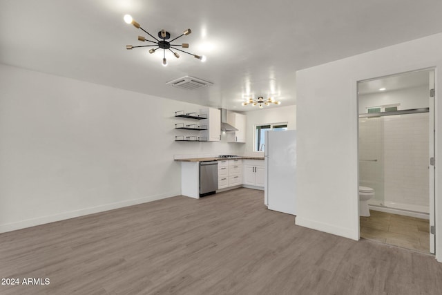 kitchen with wall chimney range hood, white refrigerator, a notable chandelier, light hardwood / wood-style floors, and white cabinetry