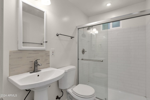 bathroom with decorative backsplash, sink, a shower with door, and toilet