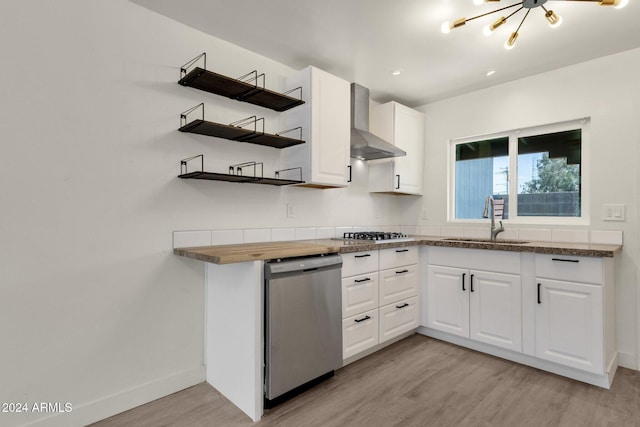 kitchen with stainless steel appliances, white cabinetry, wall chimney exhaust hood, and sink