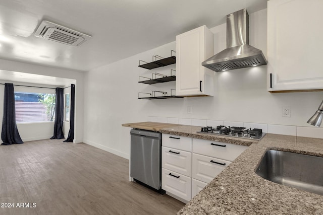 kitchen with sink, wall chimney exhaust hood, light hardwood / wood-style floors, white cabinetry, and stainless steel appliances