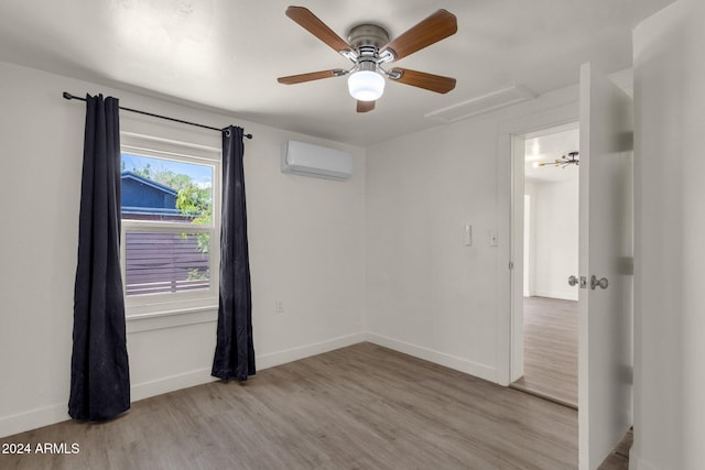 unfurnished room with ceiling fan, a wall mounted air conditioner, and light wood-type flooring