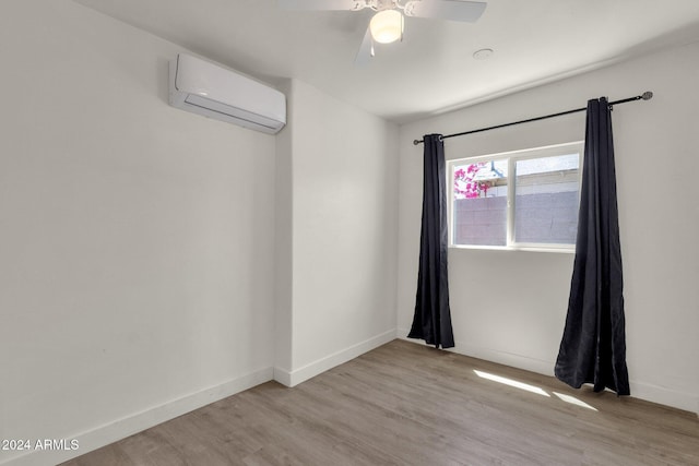 empty room with light hardwood / wood-style floors, a wall unit AC, and ceiling fan