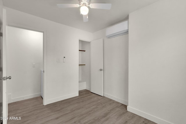 unfurnished bedroom featuring a wall mounted AC, ceiling fan, a closet, and light hardwood / wood-style floors