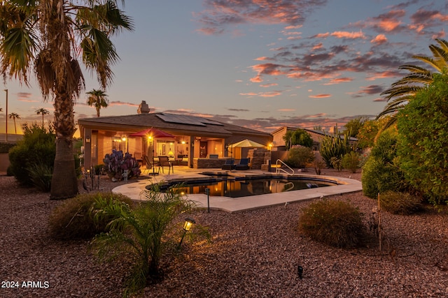 pool at dusk with a patio area