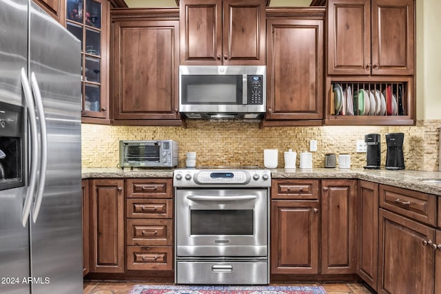 kitchen featuring light stone counters, appliances with stainless steel finishes, and tasteful backsplash