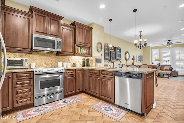 kitchen with decorative light fixtures, kitchen peninsula, appliances with stainless steel finishes, and light parquet floors