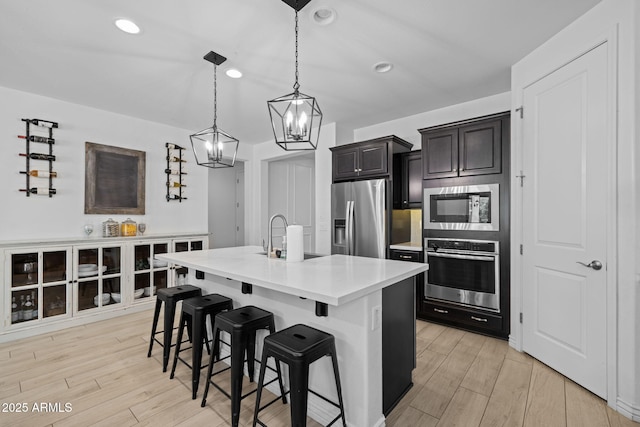 4346 S Synapse Dr, Mesa, AZ 85212 - kitchen with appliances with stainless steel finishes, a chandelier, a breakfast bar area, light countertops, and light wood-type flooring