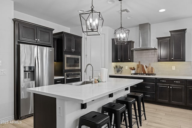 4346 S Synapse Dr, Mesa, AZ 85212 - kitchen featuring wall chimney range hood, appliances with stainless steel finishes, a chandelier, tasteful backsplash, and light countertops