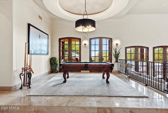 recreation room with a towering ceiling, a tray ceiling, and french doors