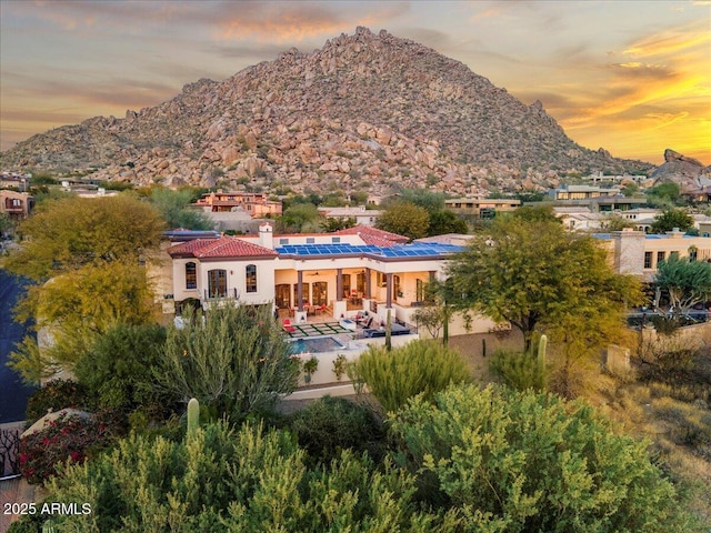 rear view of property featuring a patio area, stucco siding, a mountain view, and a tile roof