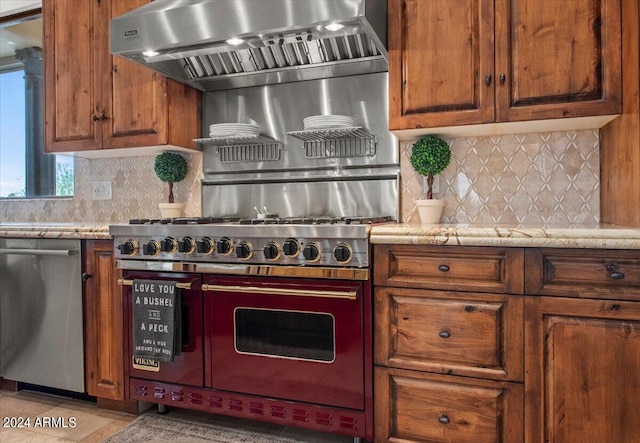 kitchen featuring light stone counters, tasteful backsplash, range hood, appliances with stainless steel finishes, and light tile patterned floors