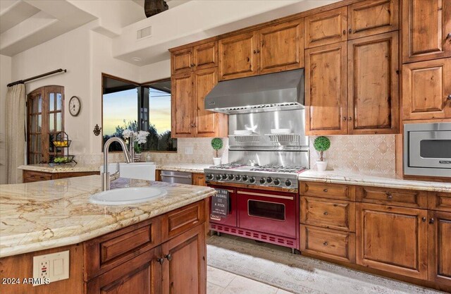 kitchen featuring decorative backsplash, light tile patterned flooring, light stone countertops, stainless steel appliances, and sink