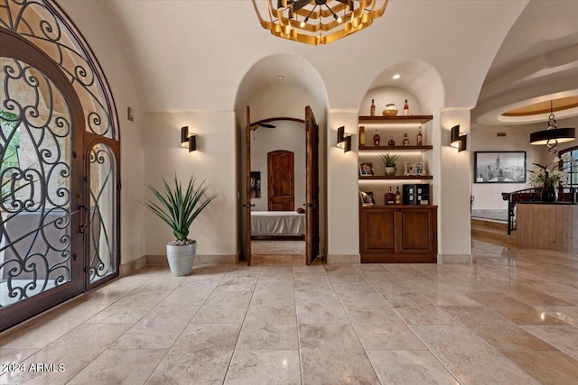 foyer featuring arched walkways, a notable chandelier, baseboards, and a towering ceiling