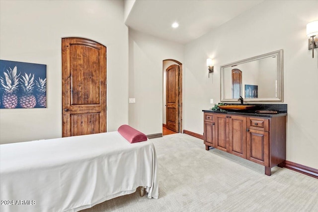 bedroom featuring baseboards, arched walkways, a sink, recessed lighting, and light carpet